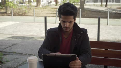 Fokussierter-Junger-Mann,-Der-Auf-Der-Straße-Ein-Digitales-Tablet-Nutzt